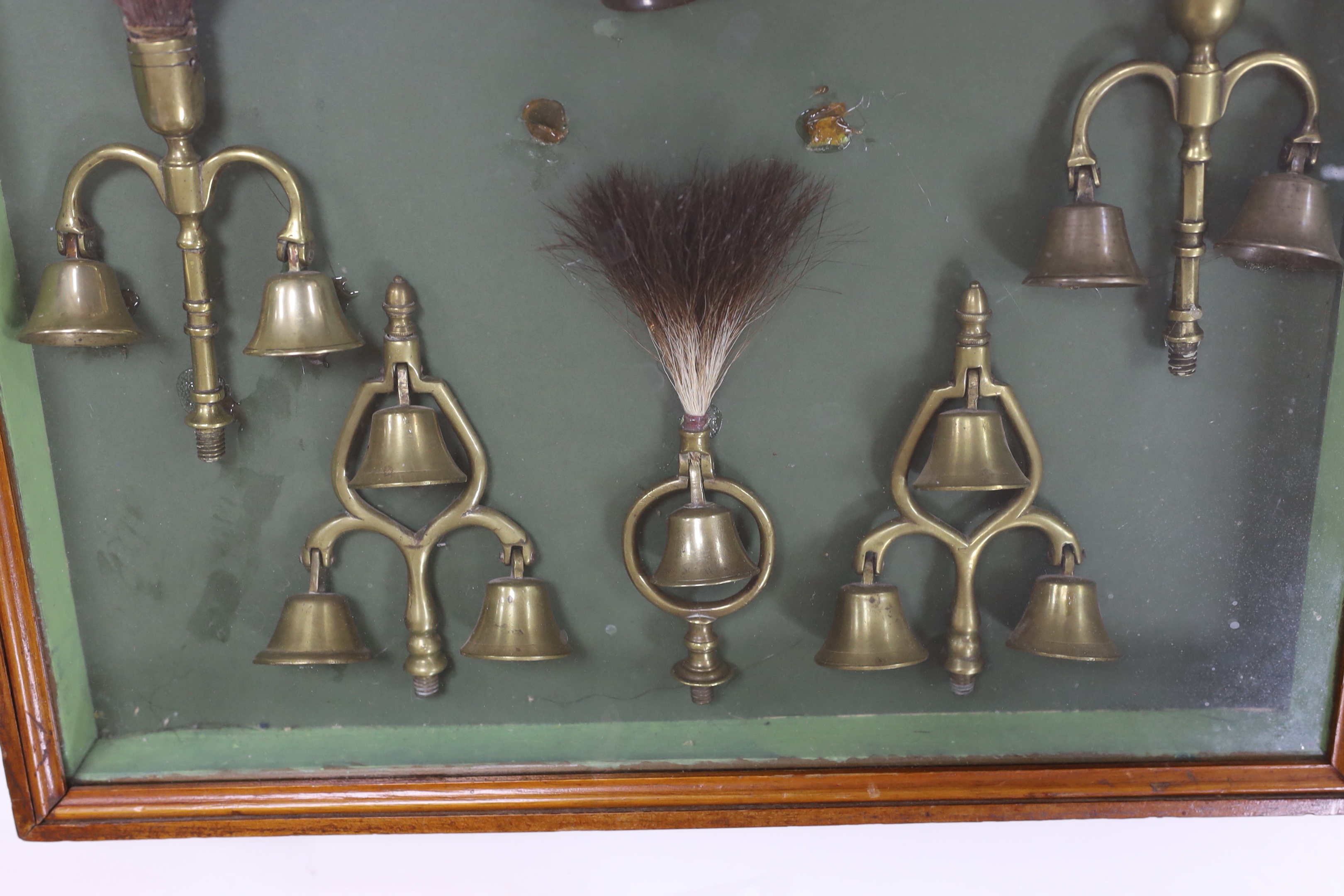 A collection of Victorian horse brass bell terrets, housed in a display case, 46cm high